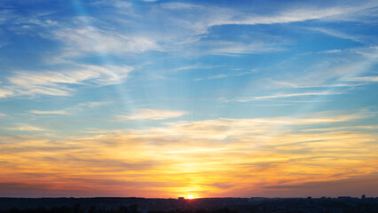 Naklejka na ściany i meble Vibrant sunrise sky background of orange and blue colours with sunrays