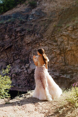 Fashionable young model in boho style dress on a background of rocks. Female beauty and style concept.