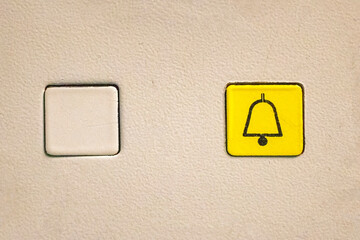 Empty elevator button and a yellow one with a bell icon for alarm