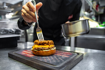 chef hand cooking cheeseburger on restaurant kitchen