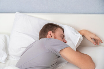 A bearded young man is sleeping in cozy bed. Happy to sleep. Healthy sleep of a man in a fresh white bed.