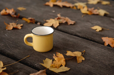 Close-up Small yellow cup on a wooden table. Autumn leaves. autumn