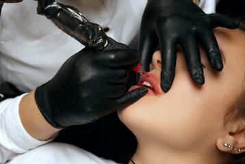 Beautician in gloves applying permanent makeup