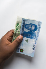 Hand holding the new Nigerian 1000 and 500 Naira notes on a white surface, Hand holding Nigeria's new currency	