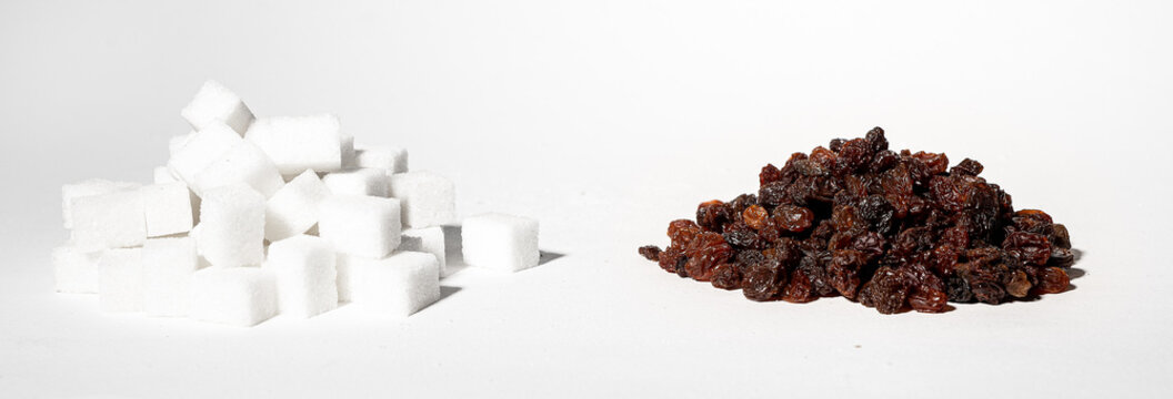 Healthy vs unhealthy sweets concept, refined sugar cubes and raisins dried grapes substitution. High quality photo