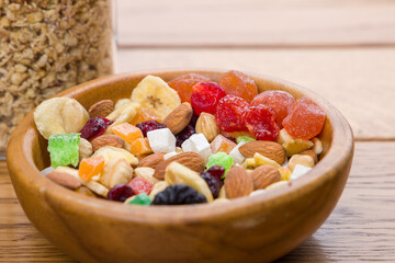 healthy breakfast. muesli with nuts and dried apricots, candied fruits and berries on wooden background
