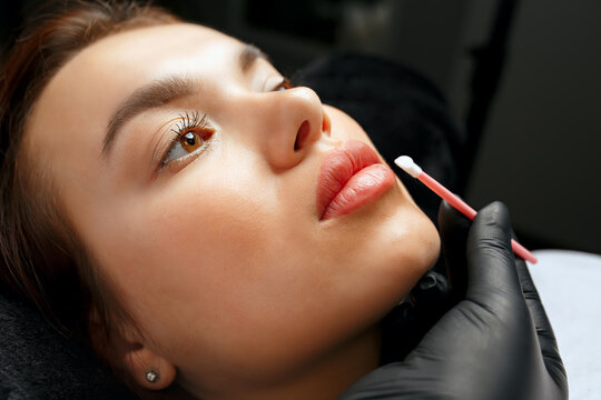 beauty master applying gel to a woman's lips after permanent makeup