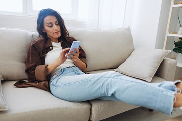 Woman blogger with phone lies at home on the couch and works freelancer online, selfie