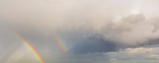 double rainbow in the sky. sky with clouds after the rain with a rainbow. heavy cumulus clouds evening sky