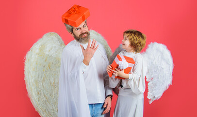 Valentines day. Father in angel costume and little son in angelic wings with present. Cute angels.