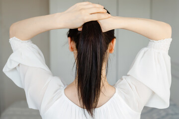Fototapeta premium Healthy Shiny Long Hair in Tale. Beautiful Girl holding her Hair in hand. Back view on white. Smooth Hairstyle with strong Hair