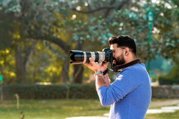 Young indian man using camera equipment at park