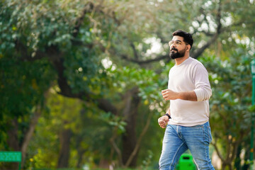 Young indian man running or jogging at park.