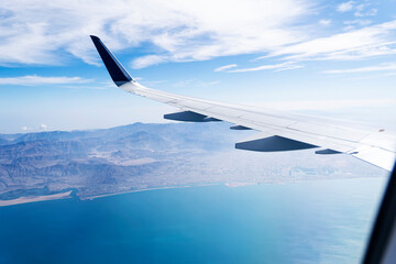 airplane wing from a porthole in flight over sea