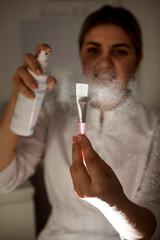 focus on brush on which beautician sprinkles with disinfectant