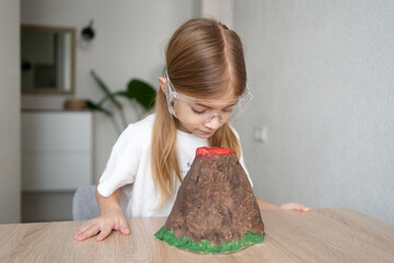 Child girl with hand made volcano. Science chemistry experiments at home.