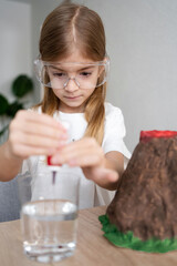 Child make chemical colour liquid, homemade science experiments with volcano. Homeschooling and distance education. 