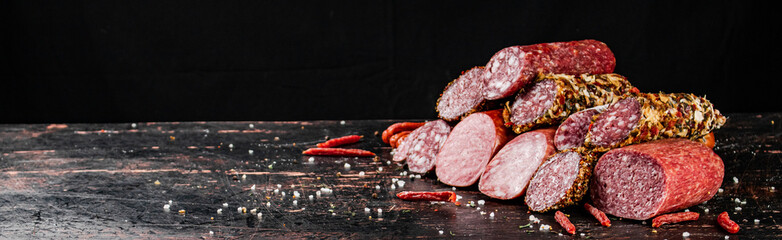 A variety of types of salami sausage with dried chili peppers on the table. 