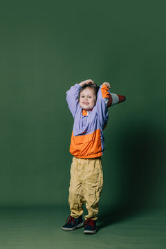 Stylish little boy with traffic cone on green background