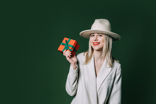 Stylish blond hair woman with gift box on green background