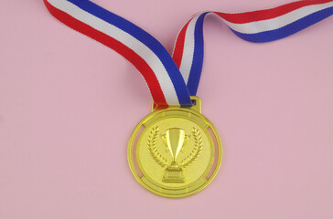 Golden medal on pink background close-up.
