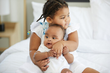 Fototapeta na wymiar African kid hugging a newborn baby or her sister on bed