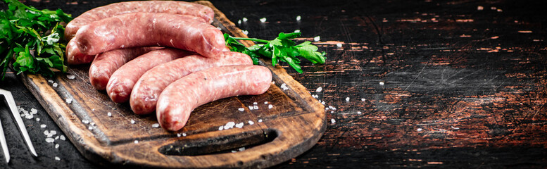 Raw sausages on a cutting board with parsley. 