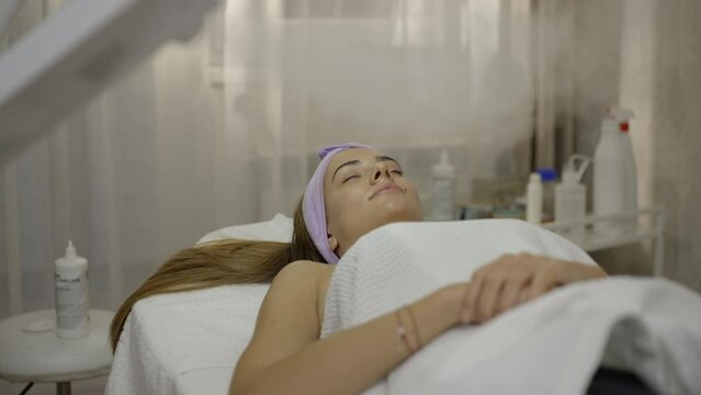 Beautiful young woman lying with closed eyes and getting ozone therapy treatment at beauty spa salon