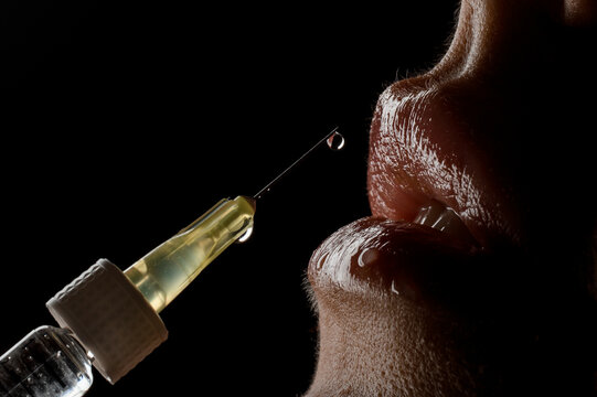macro photography of syringe needle near the female lips. Lip augmentation.