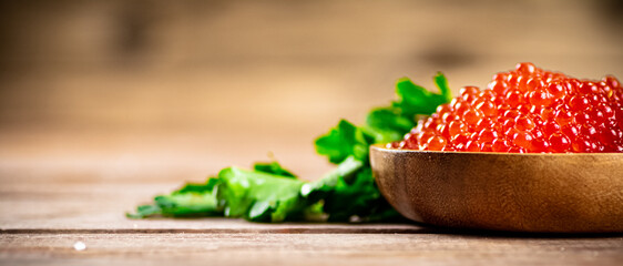 Red caviar in a plate on the table with parsley. 
