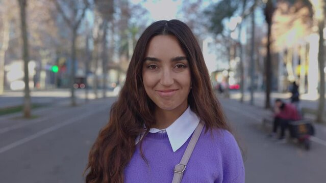 Young latin american trendy woman looking at camera smile in city urban background. Millennial happy portrait of cheerful female outdoors.