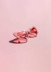 Heart shaped sunglasses on the pink background. Valentine's day concept composition