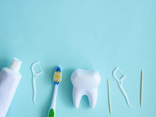 Dental concept of oral hygiene. Dental floss with plastic toothpick, big white tooth, toothpaste...