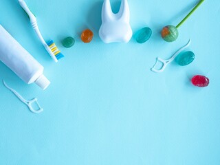 Dental concept of oral hygiene. Dental floss with plastic toothpick, brush, toothpaste, large plastic tooth, candies and sweet candies. Place for text