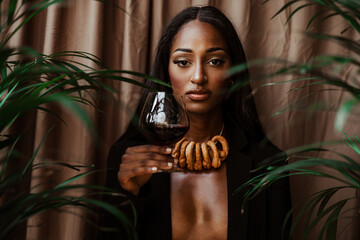 Fototapeta na wymiar A black girl with a particular necklace made of taralli and a glass of red wine in her hand.