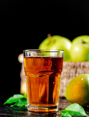 A glass of green apple juice with leaves on the table. 