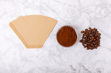 Coffee filter with ground powder on a white marble background. fragrant coffee beans for an energizing and invigorating drink. Hand Drip Coffee, Flat Lay of Manual Brew Coffee Tools