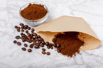 Coffee filter with ground powder on a white marble background. fragrant coffee beans for an energizing and invigorating drink. Hand Drip Coffee, Flat Lay of Manual Brew Coffee Tools