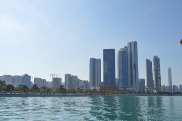 Obraz na płótnie Canvas Abu Dhabi city skyline along Corniche beach taken from a boat