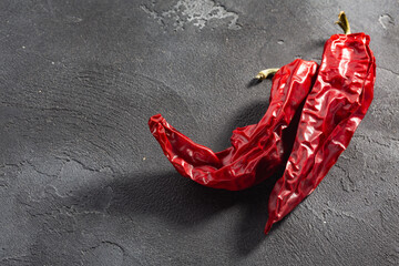 Dried Numex chile pepper pods over dark background, top view, copy space