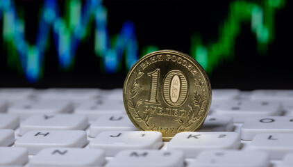 Coin of 10 Russian ruble denomination against the background of stock data chart