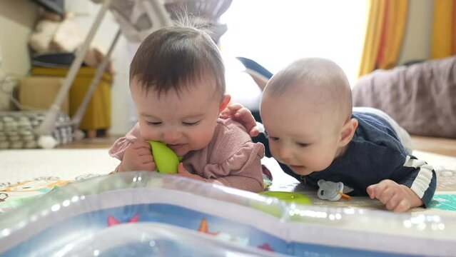 twins baby a newborn. two babies 6 months old lie on the floor playing toys. happy family kid dream concept. twin playing toy. brother and sister newborns play lifestyle at home happy family