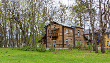 Two-storey wooden house built in the trees near the green lawn