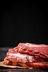 A pile of raw pork steak on the table. 