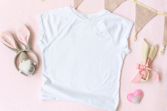 Easter mockup white t-shirt with bunny and easter eggs on pink cover background. Flatlay, top view, copyspace.