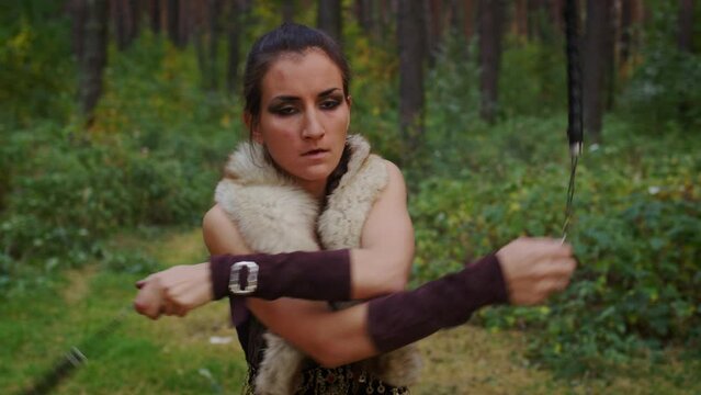 Girl in dress for performance spins ignited torches over her head and around her in boreal forest. Siberian female Shaman conjures. Woman participates in fire show in wooded place. Magic juggling