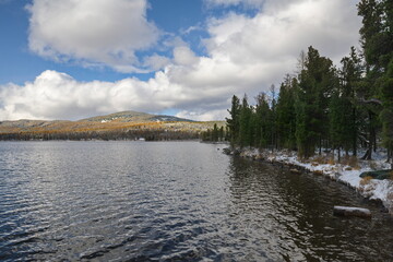 Russia. The South of Western Siberia, the Altai Mountains. Autumn view of the snow-covered shore of the mountainous Igistu-Kol lake after the first snowfall.