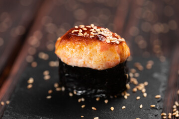 Baked shrimp gunkan on wooden background. Simple gunkan sushi with shrimp tartare with mayonnaise in minimal style. Japanese food - nigiri sushi in nori. Nigiri sushi with fish