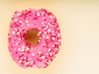 Sweet pink donut with multicolored sprinkles on yellow background. Colorful sweet dessert