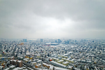 Naklejka na ściany i meble Aerial view over snow covered City of Zürich with skyline and gray cloudy winter sky on a snowy late autumn day. Photo taken December 17th, 2022, Zurich, Switzerland.